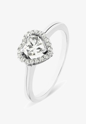 Herzförmiger Ring aus poliertem Silber. In der Mitte befindet sich ein großer klarer Edelstein, umgeben von kleineren klaren Steinen in einer Krappenfassung.
