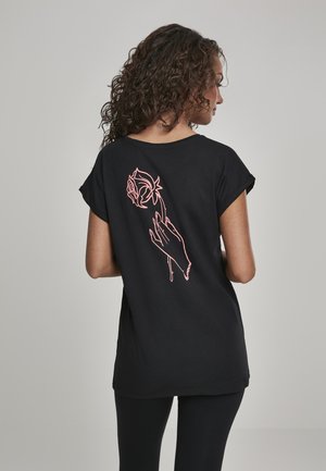 T-shirt en coton noir à manches courtes roulées, avec un motif de rose et de main en contour rose au dos. Devant uni.