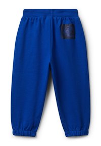 Jasnoniebieskie dziecięce dresy z elastycznymi mankietami i pasem, z małą czarną łatą z wirującą grafiką z tyłu.