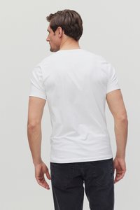 Witte t-shirt met korte mouwen, gladde textuur, klassiek ronde hals ontwerp, gedragen met een donkere spijkerbroek, gezien vanaf de achterkant.