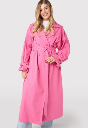 Rosa trenchcoat med bælte i taljen og hjerteformet spænde, dobbeltknaplukning og brede ærmer med bindebånd.