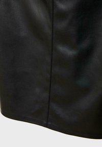 Indumento in pelle nera con una texture liscia, caratterizzato da una linea di cucitura pulita e un orlo leggermente curvo nella parte inferiore.