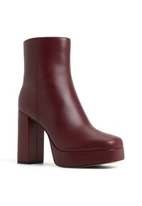 Burgundy faux leather ankle boot with a high block heel, rounded toe, and a smooth texture. Minimalist design with no visible hardware.