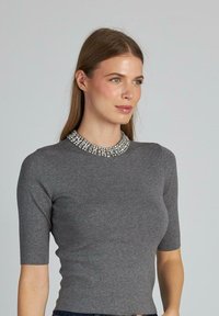 Top grigio aderente con maniche corte, caratterizzato da un colletto decorativo impreziosito da strass. Tessuto morbido e testurizzato con una silhouette snella.