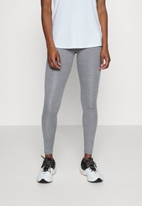 Gray leggings made of stretchy fabric, featuring a smooth texture and a form-fitting design, paired with black and white athletic shoes.