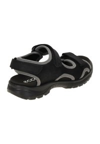 Schwarze Sandalen aus Wildleder mit grauen Akzenten. Sie verfügen über verstellbare Klettstraps und eine strukturierten Gummisohle für Grip und Komfort.