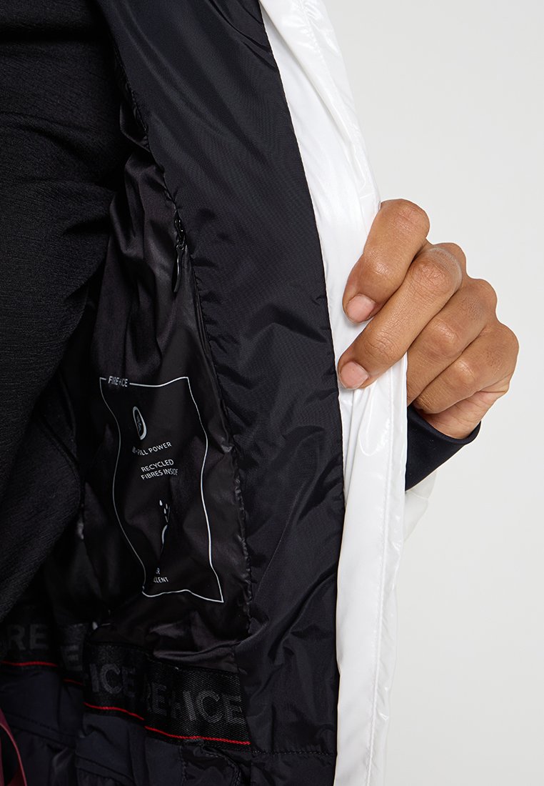 Weißer Blazer mit schwarzem Innenfutter und Etikett. Der Stoff wirkt glatt und leicht, mit einem Reißverschluss und einer Innentasche.
