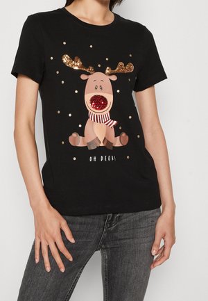 Person trägt ein schwarzes T-Shirt mit einem Cartoon-Rentier, das goldene Pailletten-Geweih, eine rote Pailletten-Nase, einen gestreiften Schal und den Schriftzug "Oh Deer!" zeigt.
