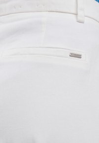 Witte denim stof met een achterzak, voorzien van een klein metalen logo-label met de tekst "BIG STAR." Soepele textuur, op maat gemaakte uitstraling.