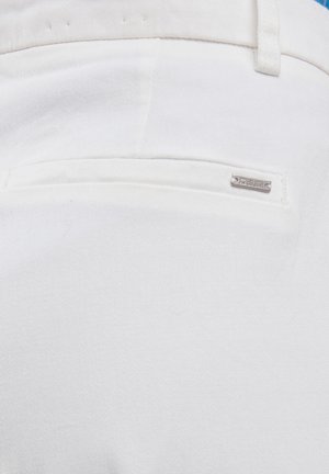 Valgest denimist kangas tagakotiga, millel on väike metallist logo silt, mis näitab "BIG STAR". Sujuv tekstuur, kohandatud disain.