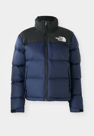 Navy blue puffer jacket with black hood and shoulders, featuring a front zip, stitched pattern, and logo on the left chest area.