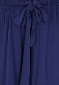 Navy blue kangas kera pehmoisen tekstuurin, jossa on solmittu nauhakiinnitys vyötäröllä ja kerätty ommel rentoa istuvuutta varten.