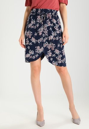 Jupe florale marine à taille élastique et avec cordon de serrage. Présente un design enroulé avec des motifs floraux roses et blancs. Texture de tissu lisse.