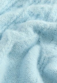 Tissu tricoté bleu clair doux avec une texture duveteuse et des plis subtils créant des ombres et des reflets doux.