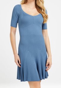 Hedvábné modré šaty s krátkými rukávy, kulatým výstřihem a rozevlátou sukní mají vertikální pruhy a švy v oblasti pasu.