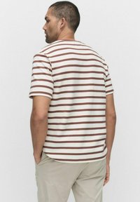 Kortärmad t-shirt med rundad halsringning i krämfärgad med bruna horisontella ränder; mjukt material, normal passform, synlig sömnad och rak fåll.