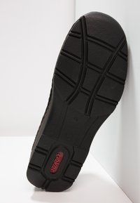 Zwarte schoenzool met een gestructureerd rubberoppervlak, voorzien van diepe profilering en een centraal rood logo. Hoekige vorm met versterkte randen.