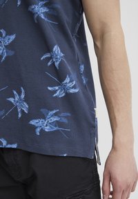 Mørkeblå bomull t-skjorte med lysebl�å blomster mønster, med en sidesliss og en liten merkeetikett i nederkant.