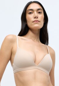 Beige, háromszögletű bralette vékony, állítható pántokkal, varrás nélküli kialakítással és puha, sima textúrával. Egyszerű és minimalista stílus.