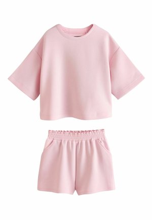Set casual rosa tenue con top oversize a maniche corte e pantaloncini con vita elasticizzata e tasche laterali.