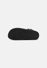 Juodas batų padas su tekstūruota guma, turintis griovelius sukibimui. Paženklintas "KARL LAGERFELD" stačiakampio formos logotipu.