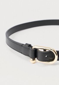 Melnas ādas josta ar zelta toņa ovālu sprādzi, gludu tekstūru un nelielu dekoratīvu metāla bumbu uz sprādzes tuvumā.