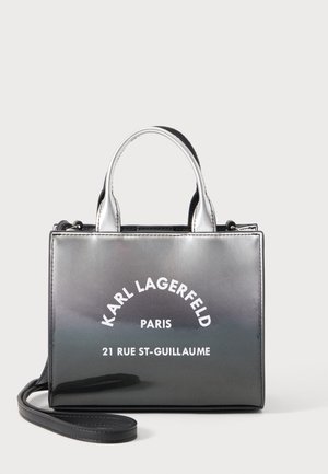 Sac à main Karl Lagerfeld noir et argenté brillant avec poignées supérieures et bandoulière amovible, marqué du texte « Paris 21 Rue St-Guillaume ».