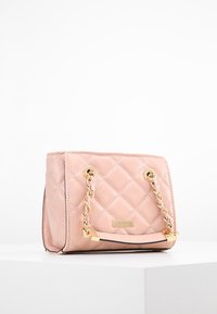 Quilted pink leather handbag with gold chain handles, a structured shape, and a small rectangular design, featuring a logo plaque on the front.