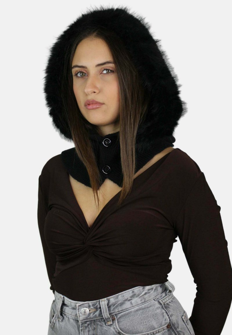 Cappuccio in ecopelliccia nera con colletto aderente e dettagli a bottone, abbinato a una maglia marrone con scollatura a V profonda e jeans a vita alta grigio chiaro.