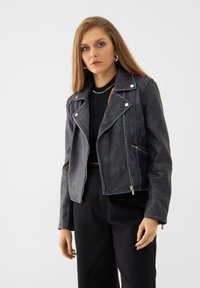 Black leather biker jacket with silver zippers, snap fasteners, and detailed stitching; cropped design, smooth texture.