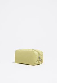 Bolsa de tela amarilla con forma rectangular, cierre de cremallera, textura suave y un brillo sutil. Diseño compacto y funcional.