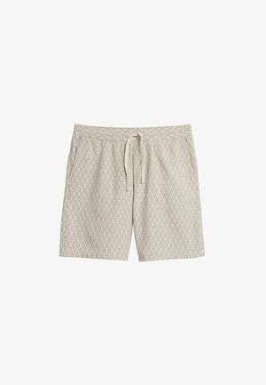 Beige zwembroek met een diamantpatroon, elastische tailleband en verstelbare trekkoord. De stof heeft een zachte textuur.