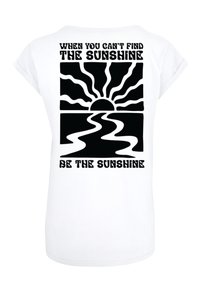 White t-shirt featuring black graphic design of a sun with rays above wavy lines. Text reads, "WHEN YOU CAN'T FIND THE SUNSHINE, BE THE SUNSHINE."