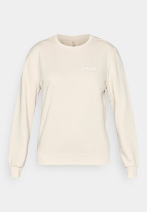 Cream sweatshirt with a round neck, long sleeves, and ribbed cuffs. Features white "LIMITLESS" text and a minimalist design. Soft texture.