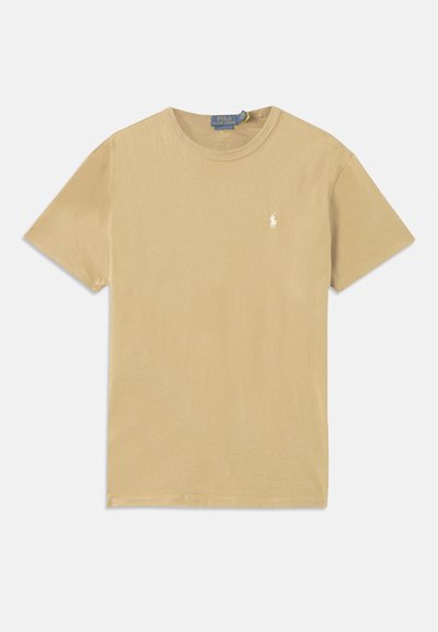 Μπεζ βαμβακερό t-shirt με στρογγυλή λαιμόκοψη και κοντά μανίκια. Διαθέτει ένα μικρό λευκό λογότυπο στο στήθος και απλή υφή.