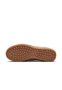 Nike-sneakersula med en brun gummitextur, med ett mönster för hög grepp och en lätt kurvatur vid tåpartiet. Logotyp synlig.