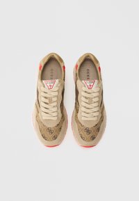 Beżowe sneakersy z wzorem logo, wykonane z zamszu i tkaniny, z płaskimi sznurowadłami, czerwonymi akcentami na pięcie i teksturowaną podeszwą.