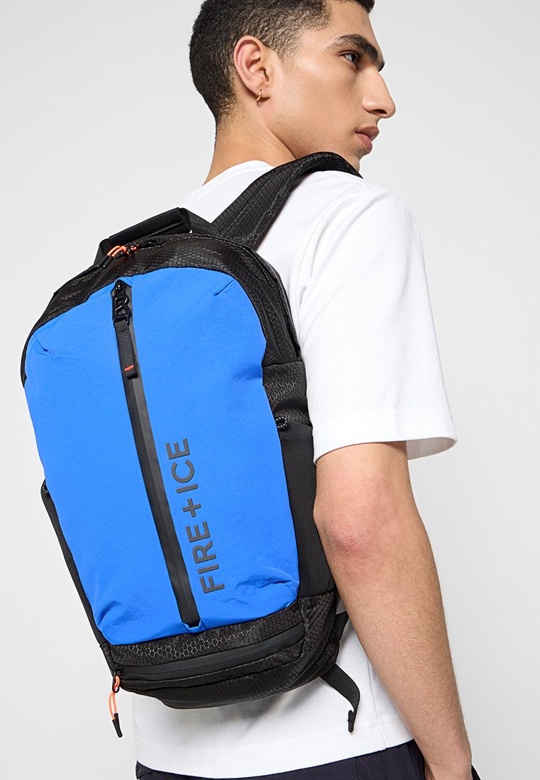 Schwarzer und blauer Rucksack mit glatter Textur, ausgestattet mit einem zentralen Reißverschluss, markantem "FIRE + ICE"-Logo und verstellbaren Schultergurten.