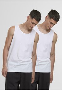 Valge puuvillane lõhikuga tank top ümarate kaelusega ja sirge hemiga, millel on sile tekstuur ja ilma nähtavate mustrite või disainideta.