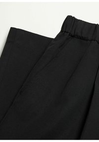 Pantalons noirs avec une taille élastique, dotés de deux poches latérales et d'une texture lisse avec des détails de couture minimaux.