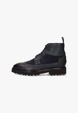 Schwarzlederne und Wildlederne Brogue-Ankle-Boots mit Profilsohle und Schnürverschluss, ausgestattet mit Zugschlaufe an der Ferse.