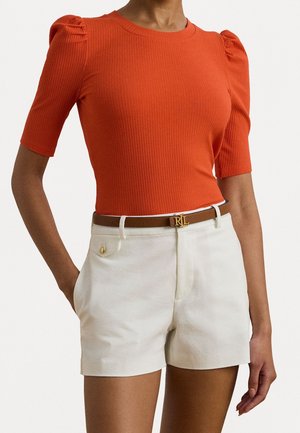 Top naranja ajustado de manga corta con textura acanalada y pantalones cortos crema con un detalle de botón dorado, combinado con un cinturón marrón con un logo dorado.