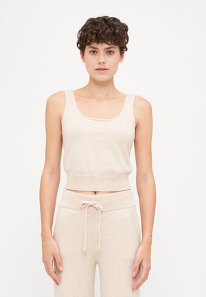 Débardeur court en tricot beige avec un décolleté en forme de scoop et des bretelles larges, associé à un pantalon léger à cordon de serrage assorti.