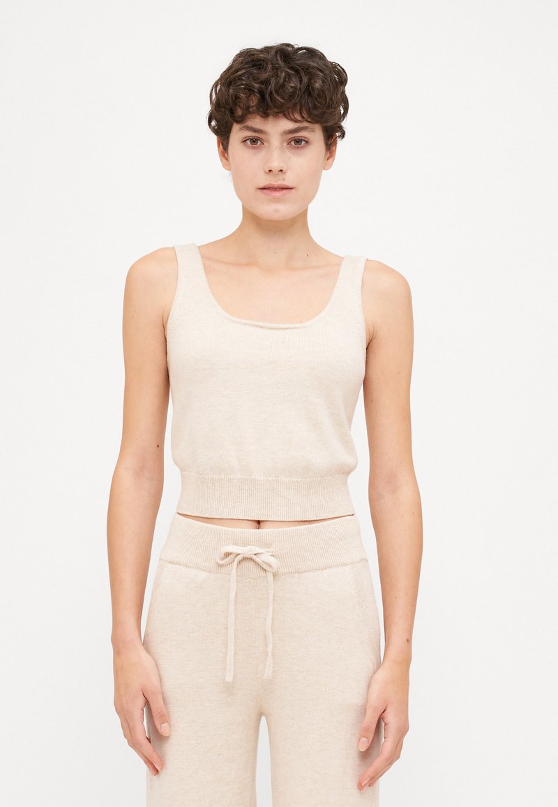 Βεραμάν πλεκτό κοντό τοπ με στρογγυλή λαιμόκοψη �και φαρδιές τιράντες, συνδυασμένο με ελαφριά παντελόνια με κορδόνι που ταιριάζουν.