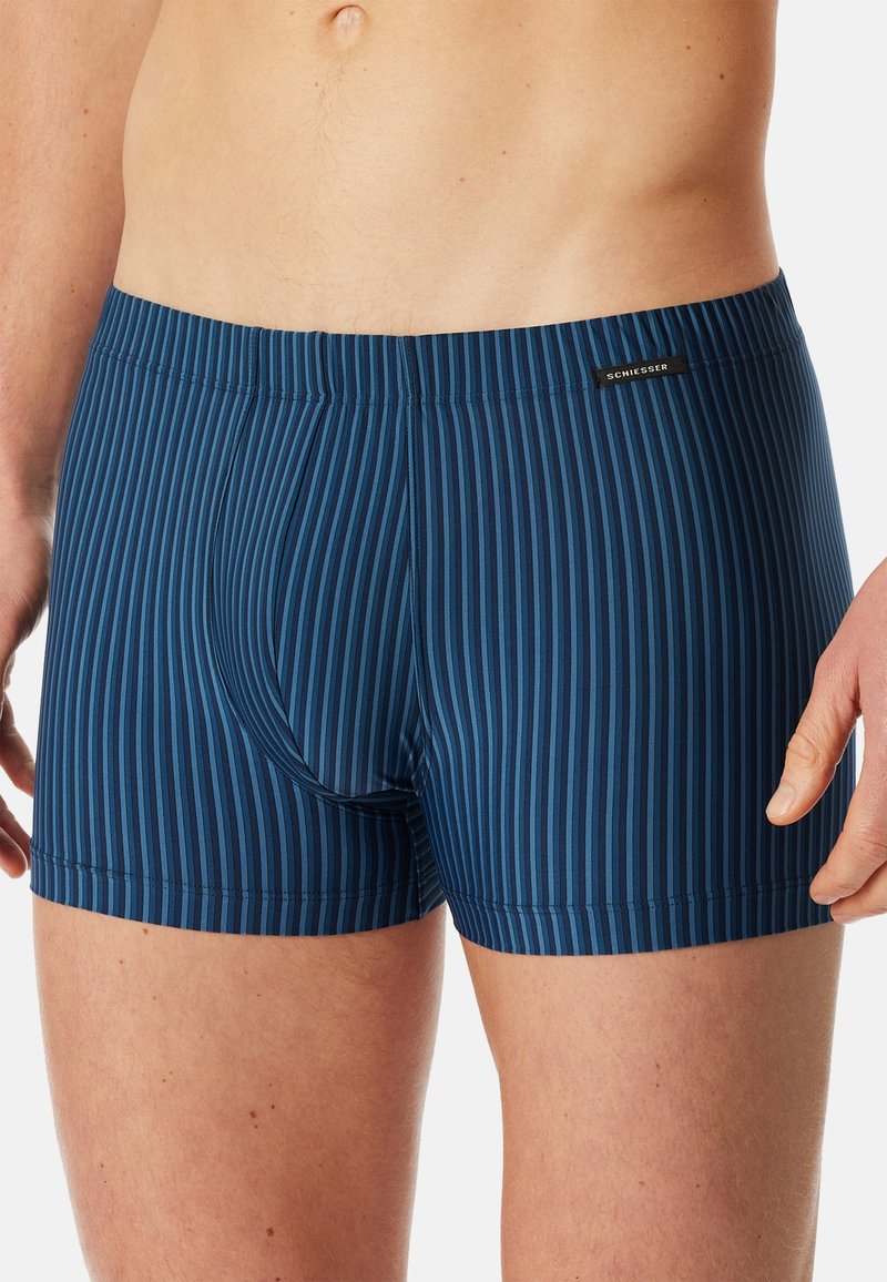 Navy blue boxer shorts feature vertical stripes in varying shades, smooth texture, elastic waistband, and a logo label at the waist.