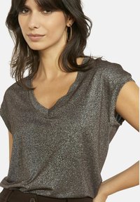 Top a maniche corte, scuro e glitterato con scollatura a V, realizzato in materiale scintillante, caratterizzato da una vestibilità morbida e una texture liscia.