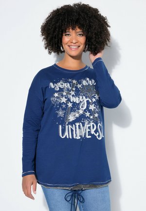 Marineblaues Langarmshirt mit Rundhalsausschnitt, versehen mit silbernem Grafikttext und Sternmustern. Etwas länger geschnitten mit einem Kordelzug am Saum.