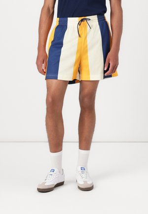 Mřížkové sportovní šortky v modré, žluté a krémové barvě. Obsahují elastický pas se šňůrkou a kontrastní postranní pruhy.