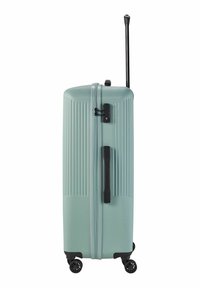 Valise rigide vert menthe avec rainures verticales, poignée noire, trolley rétractable et quatre roulettes pivotantes pour une mobilité aisée.