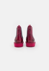 Blizgantys bordo spalvos odiniai kulkšniniai batai su brogue raštu ir tamsiai mėlynomis šoninėmis dalimis. Turi ryškiai rožinį pado ir užtrauktuką gale.